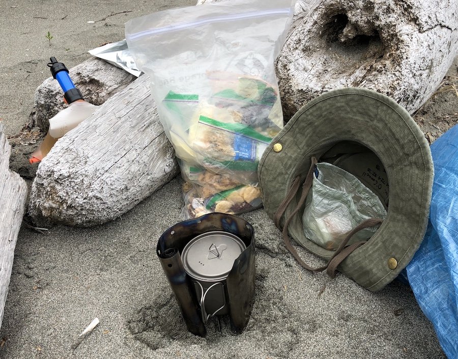 Cooking dinner on a tiny Esbit Stove using logs to cut down on the wind at Guise Bay, Cape Scott Trail, Cape Scott Provincial Park