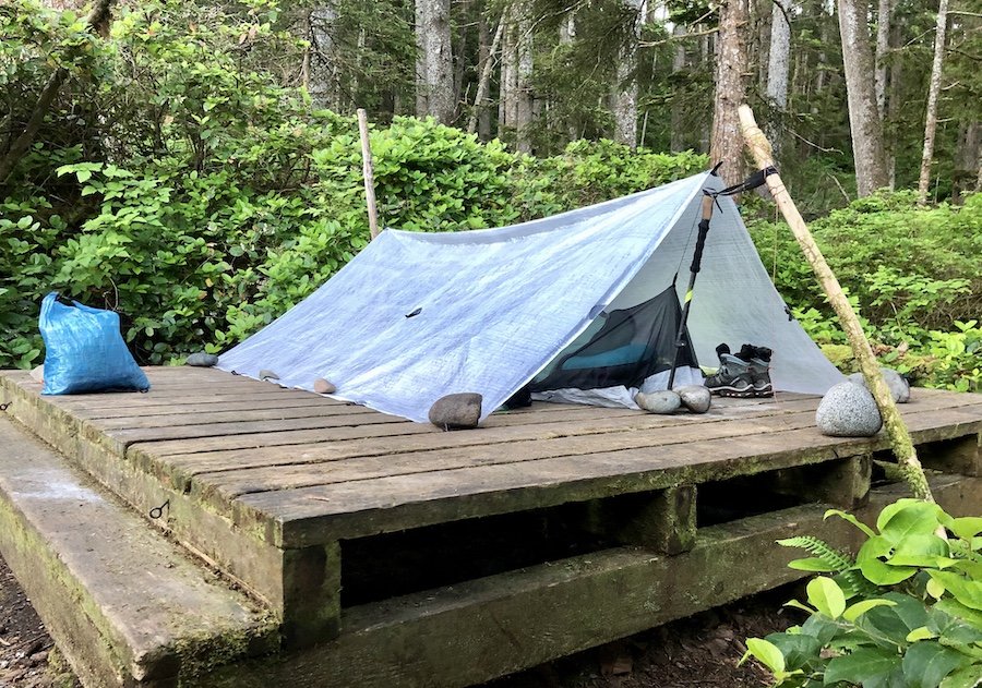 Tarp and bivy set-up using rocks and branches at Laura Creek, North Coast Trail